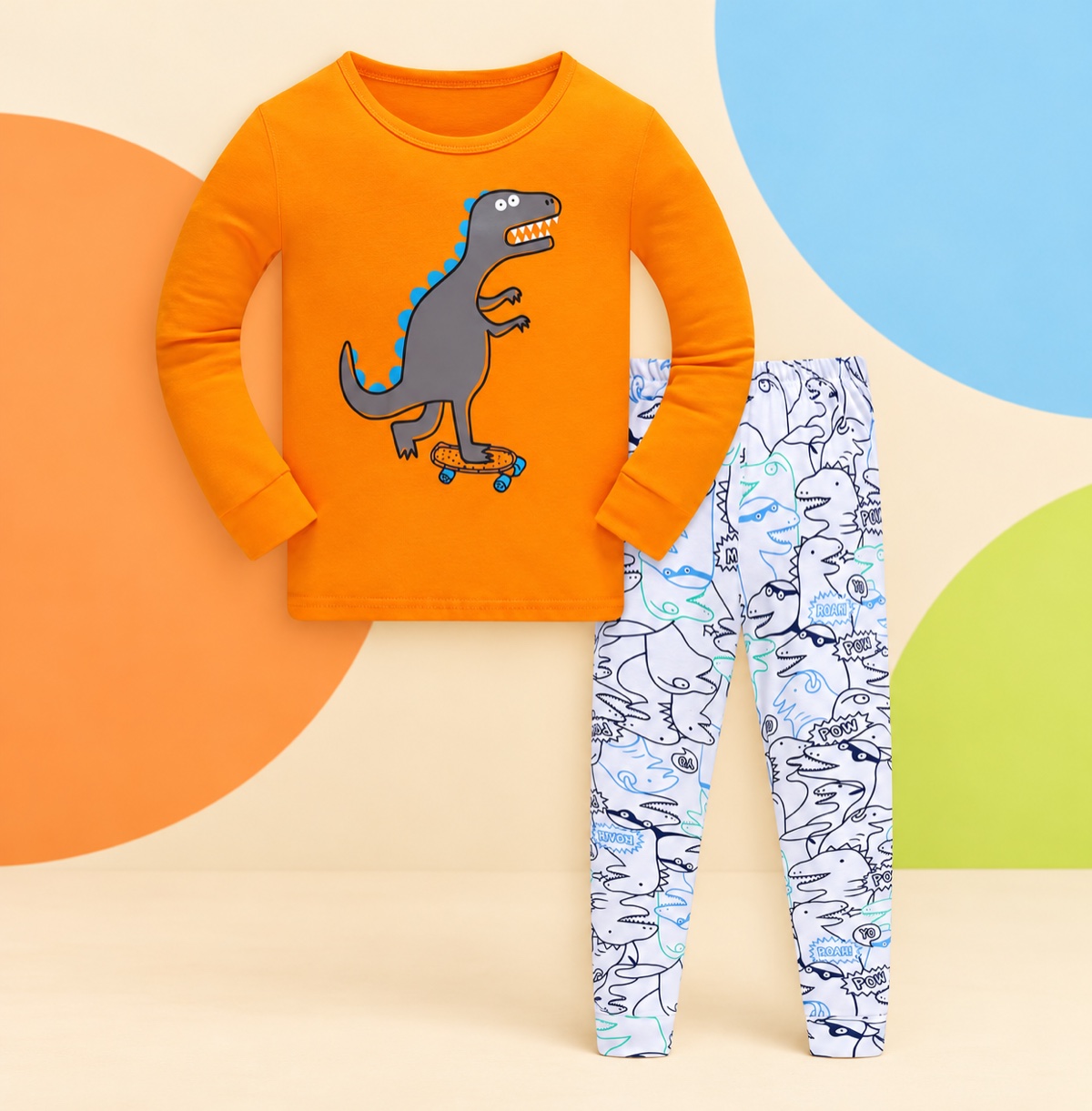 Orange dinosaur children’s pajama set on a cream and colorful studio background
