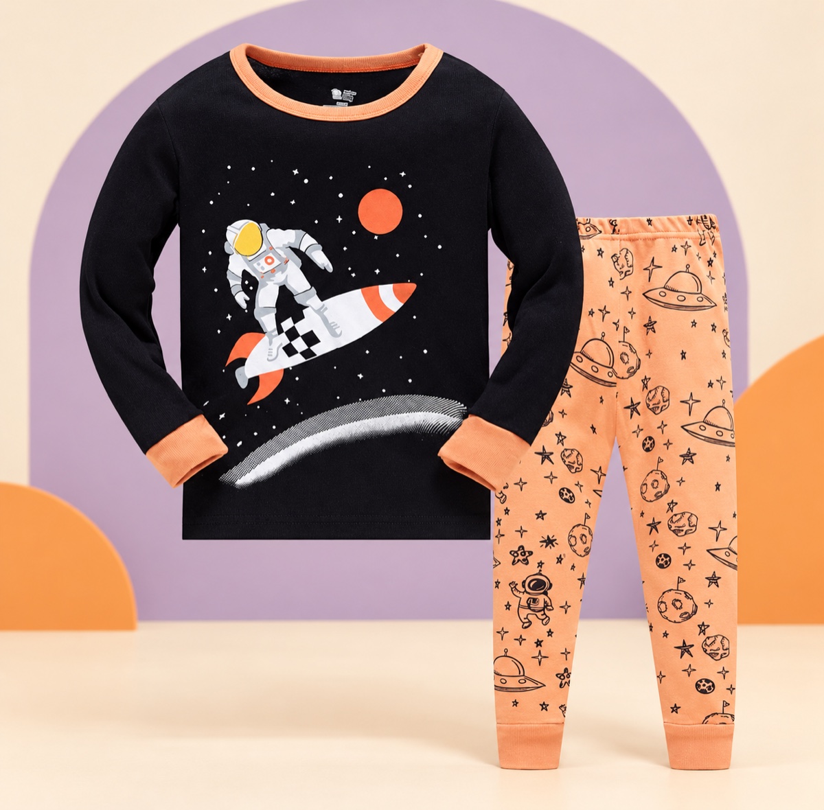 Black and peach space print children’s pajama set on a cream and lavender studio background