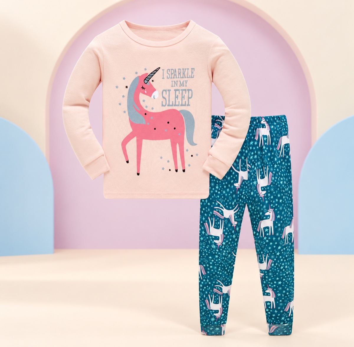 Pink unicorn children’s pajama set on a cream and lavender studio background